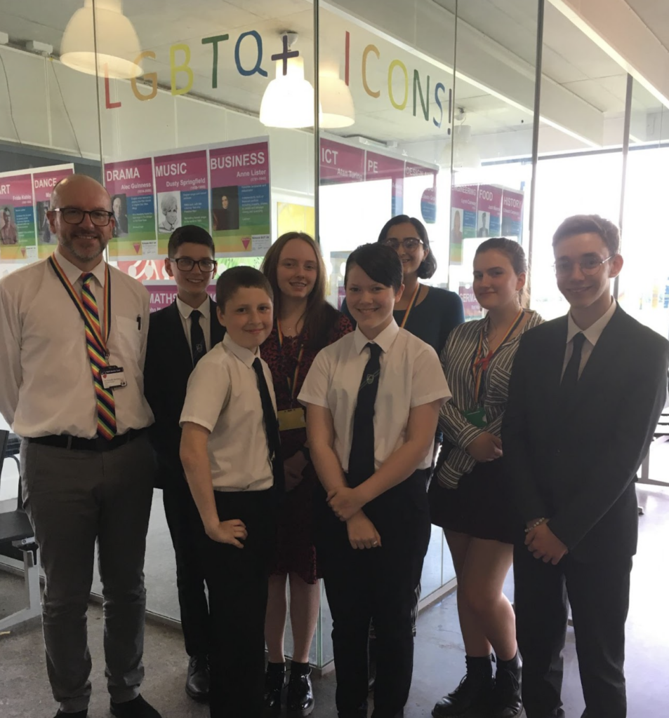 A small group of students are pictured stood alongside a member of staff in a hallway area of the academy building.