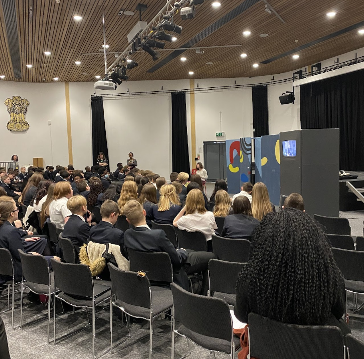 Students are seen sat down together in the main hall to watch a performance on the stage.