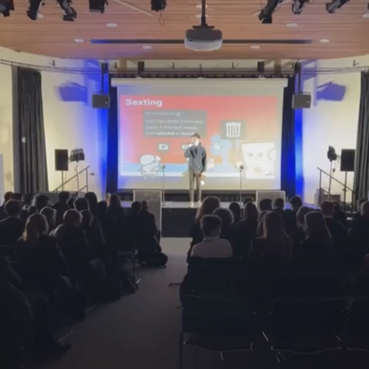 A photo showing Leigh Academy students gathered in the main hall of the academy building, listening to a speaker delivering a presentation to them.