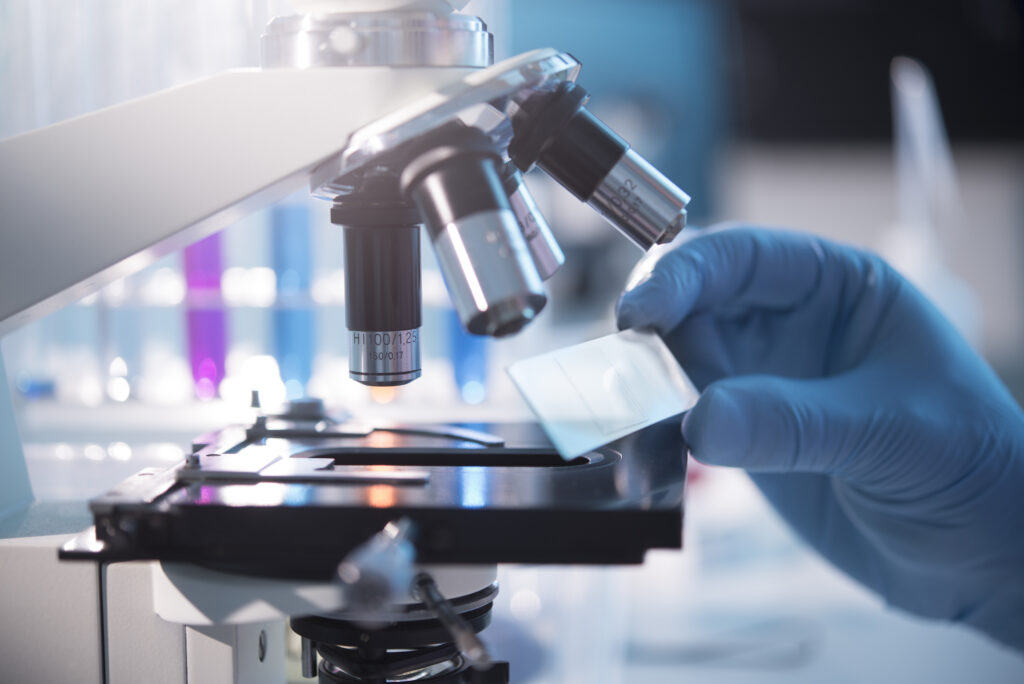 A scientist placing a slide under a microscope.